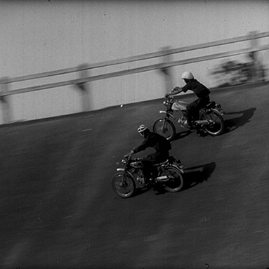 Dust and Metal. Black and White image of two people racing on motorcycles.